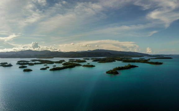 Coastal water with small islands and mountains in the background