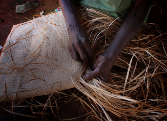 Close-up of an Indigenous person’s hands weaving a bag.