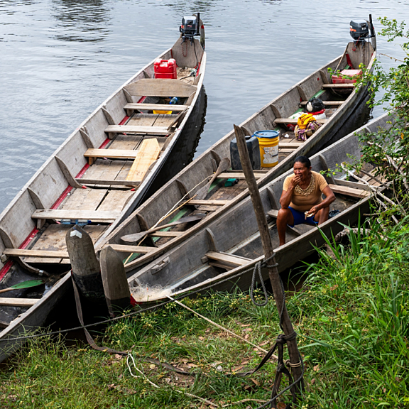 Three boats in water docked alongside each other with one person in one of the boats.
